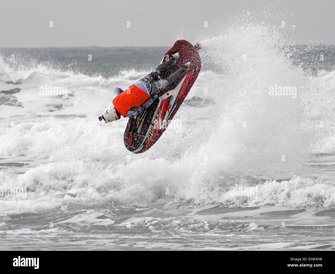 Maschio di jet ski concorrente esegue l'azione dell'antenna si sposta nella rottura grande surf su Newquay Fistral Beach Foto Stock