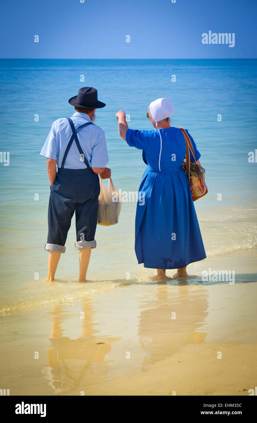 Amish giovane vestito nel loro modo tradizionale pagaia in shallow surf a Siesta Key Beach a Sarasota, FL Foto Stock