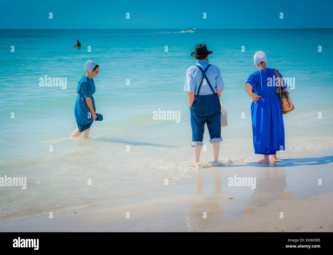Tre Amish, vestito nel loro modo tradizionale pagaia in shallow surf a Siesta Key Beach a Sarasota, FL, Stati Uniti d'America Foto Stock