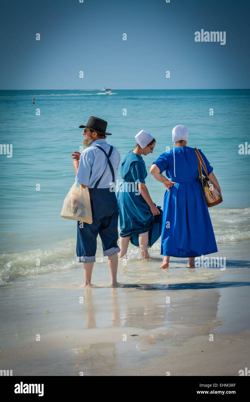 Tre Amish, vestito nel loro modo tradizionale pagaia in shallow surf a Siesta Key Beach a Sarasota, FL Foto Stock