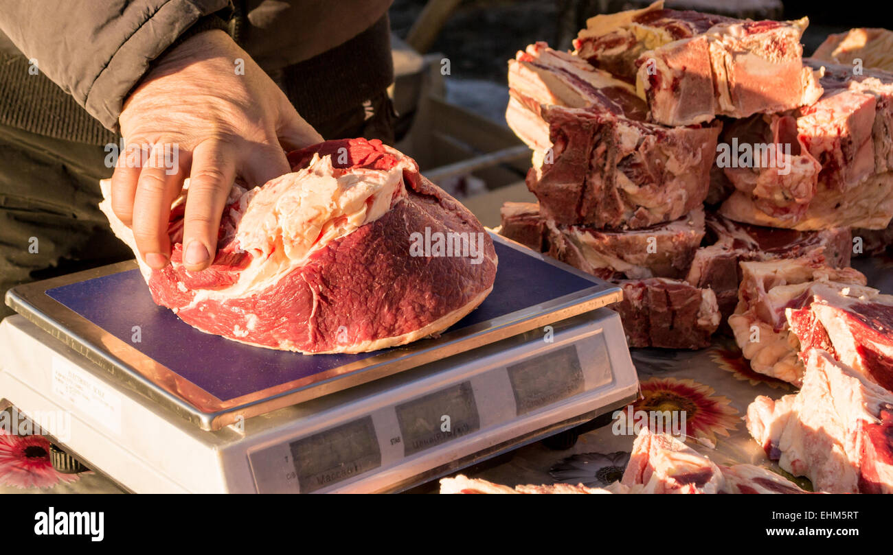 Un venditore pesa materie non cotti a base di carne di manzo prima del confezionamento Foto Stock
