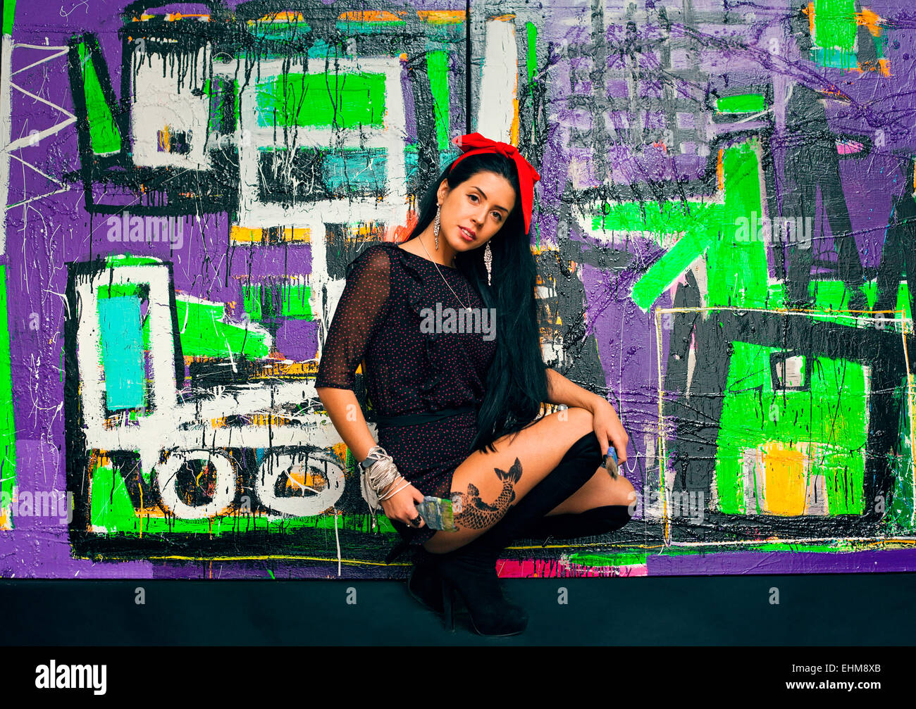 Donna in posa di fronte di colorati graffiti wall Foto Stock