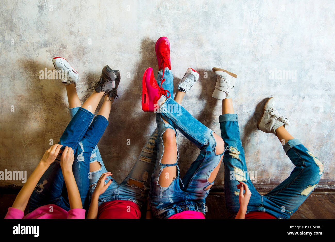 Donne caucasici ammirando le loro sneakers contro la parete Foto Stock