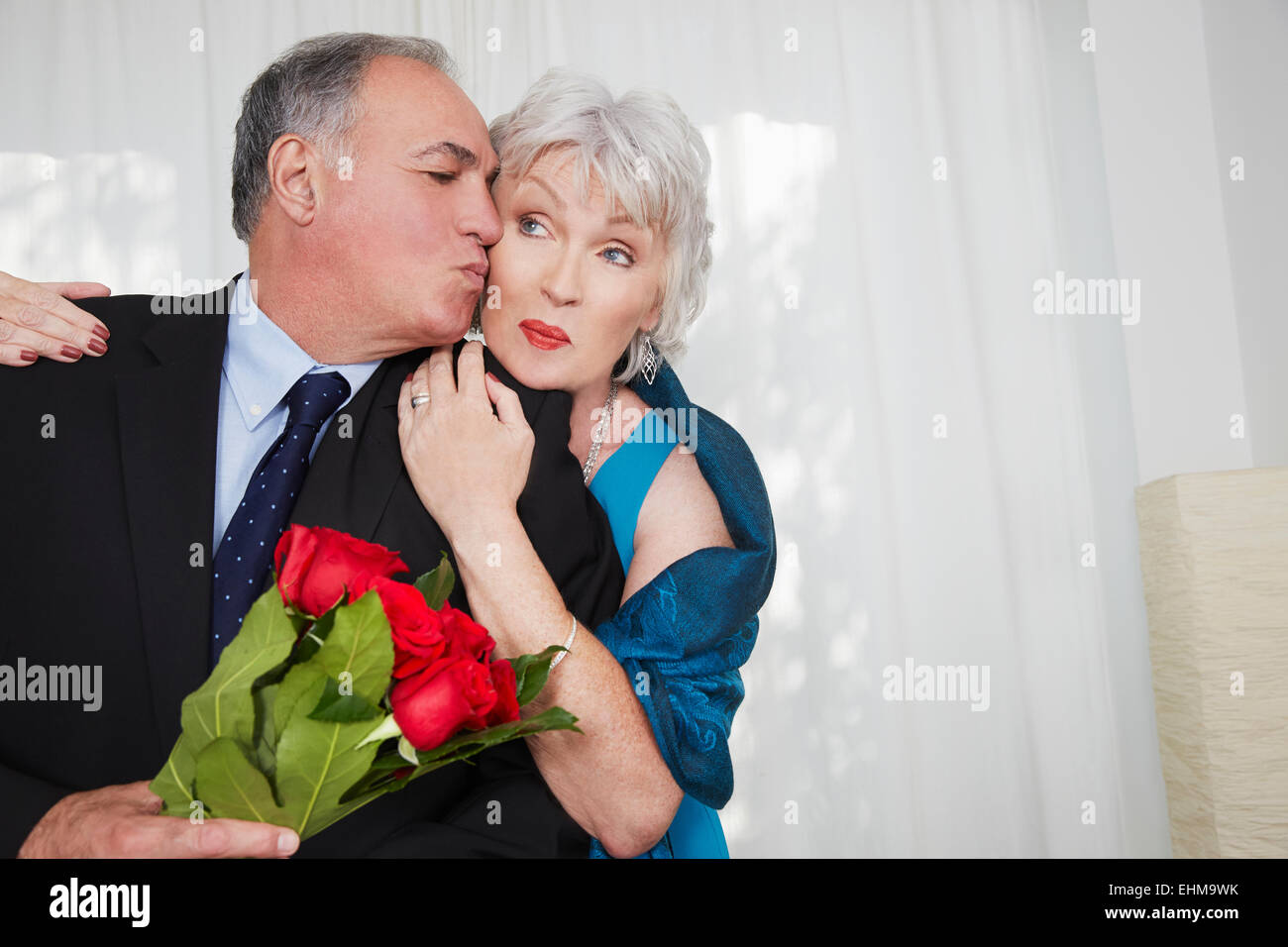 Coppia di anziani in abbigliamento formale kissing Foto Stock