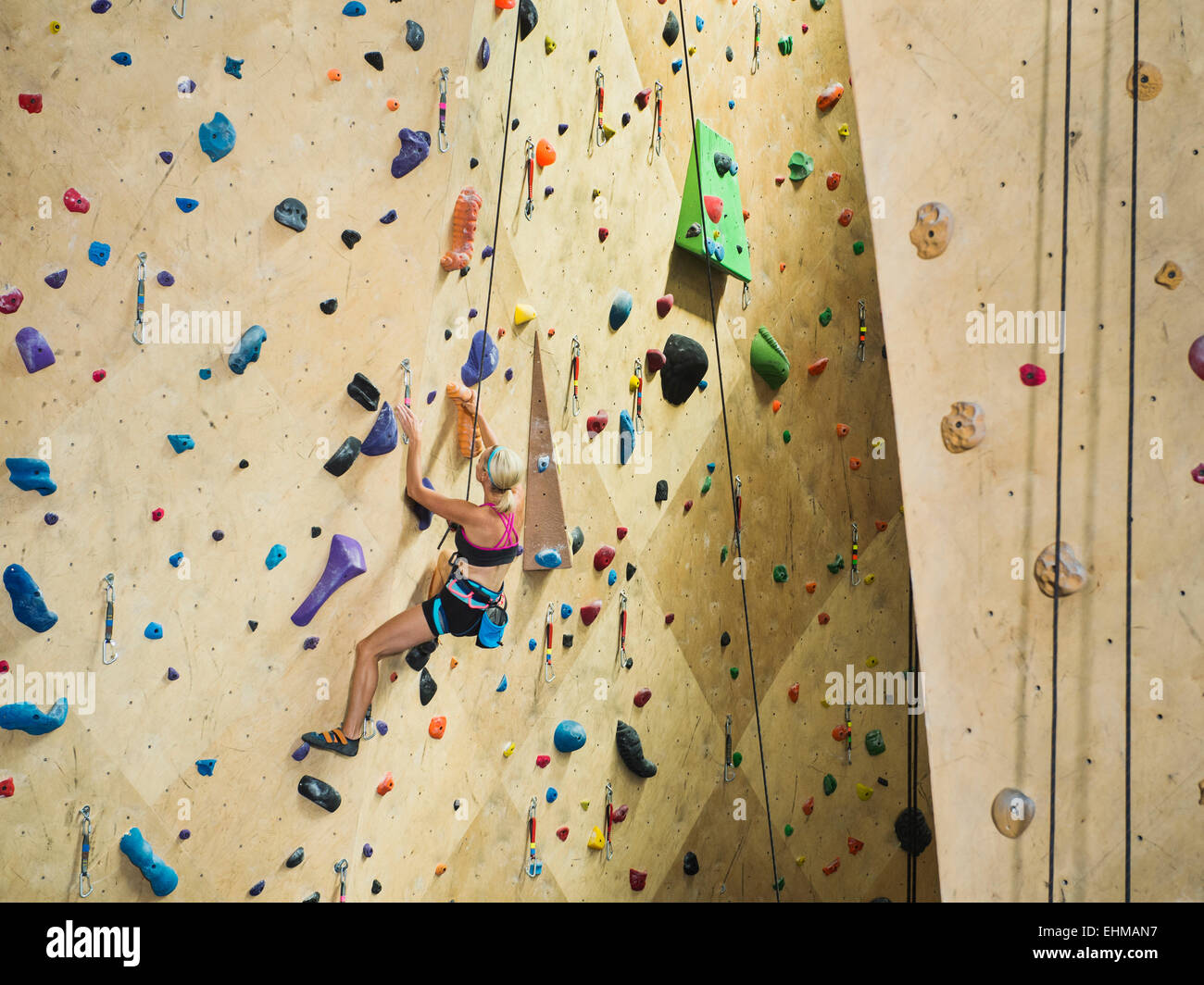 La donna caucasica arrampicata indoor parete di roccia Foto Stock