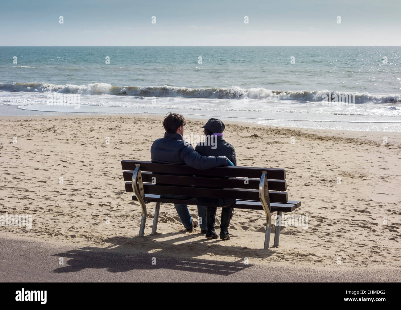 Giovane seduto sul sedile passeggiata a mare, West Beach, Bournemouth Dorset, England, Regno Unito Foto Stock