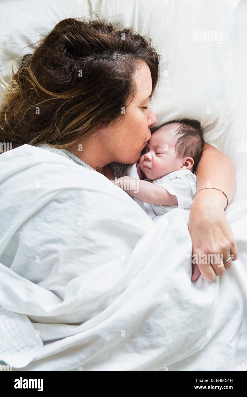 Elevato angolo di visione della madre di baciare il bambino a letto Foto Stock
