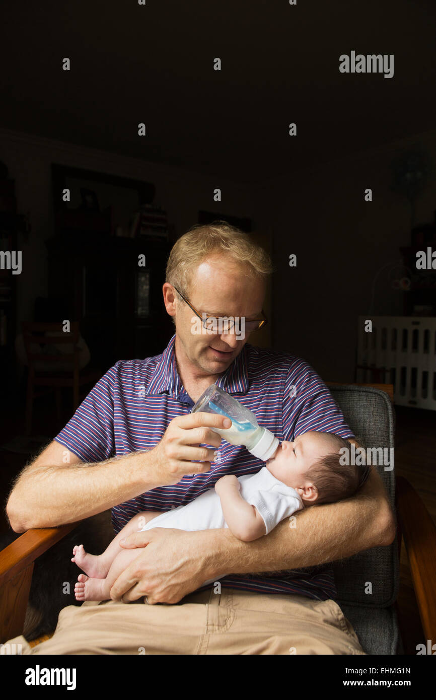Padre biberon baby in poltrona Foto Stock