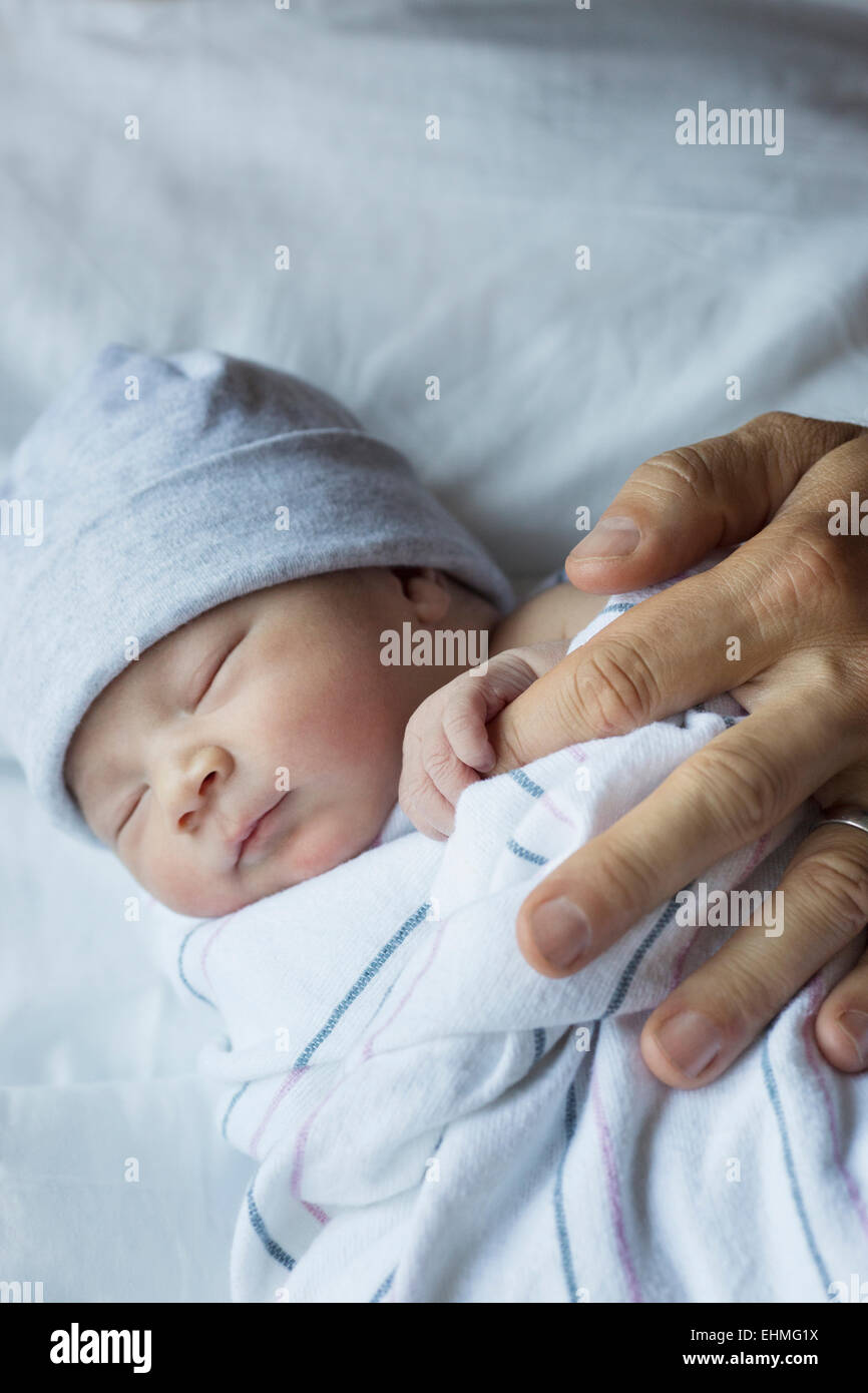 Close up del neonato tenendo il dito del padre Foto Stock