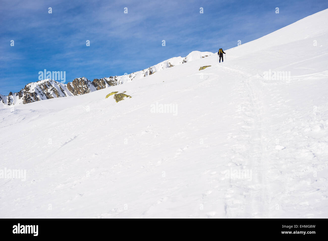 Tour sciatore escursionismo in salita verso la vetta della montagna sotto un sole splendente nelle Alpi italiane. Concetto di conquista di avversità. Foto Stock