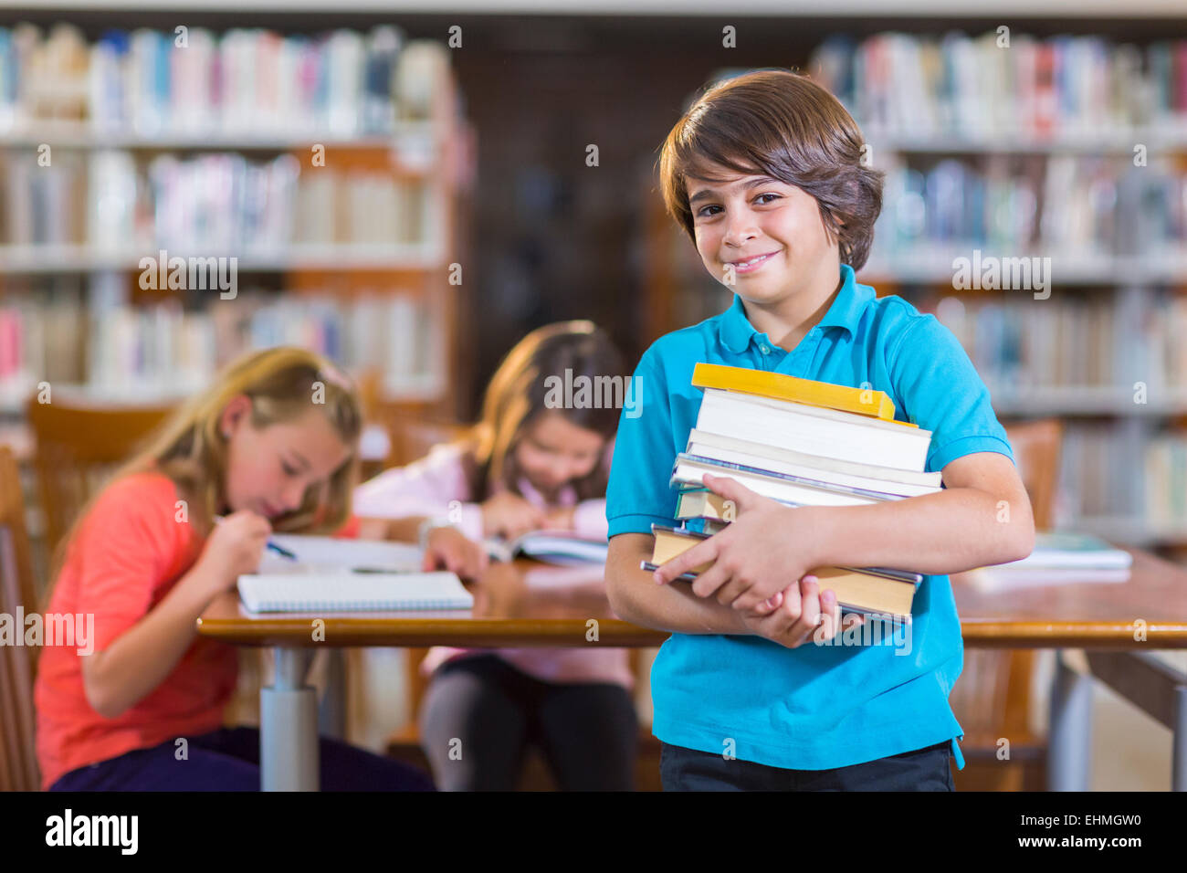 Lo studente che trasportano pila di libri in biblioteca Foto Stock