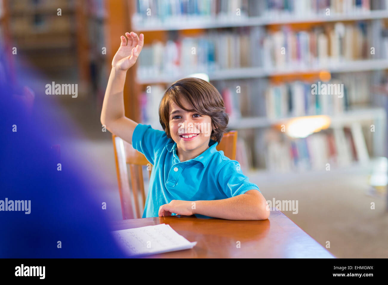 Studente alzando la mano in libreria Foto Stock