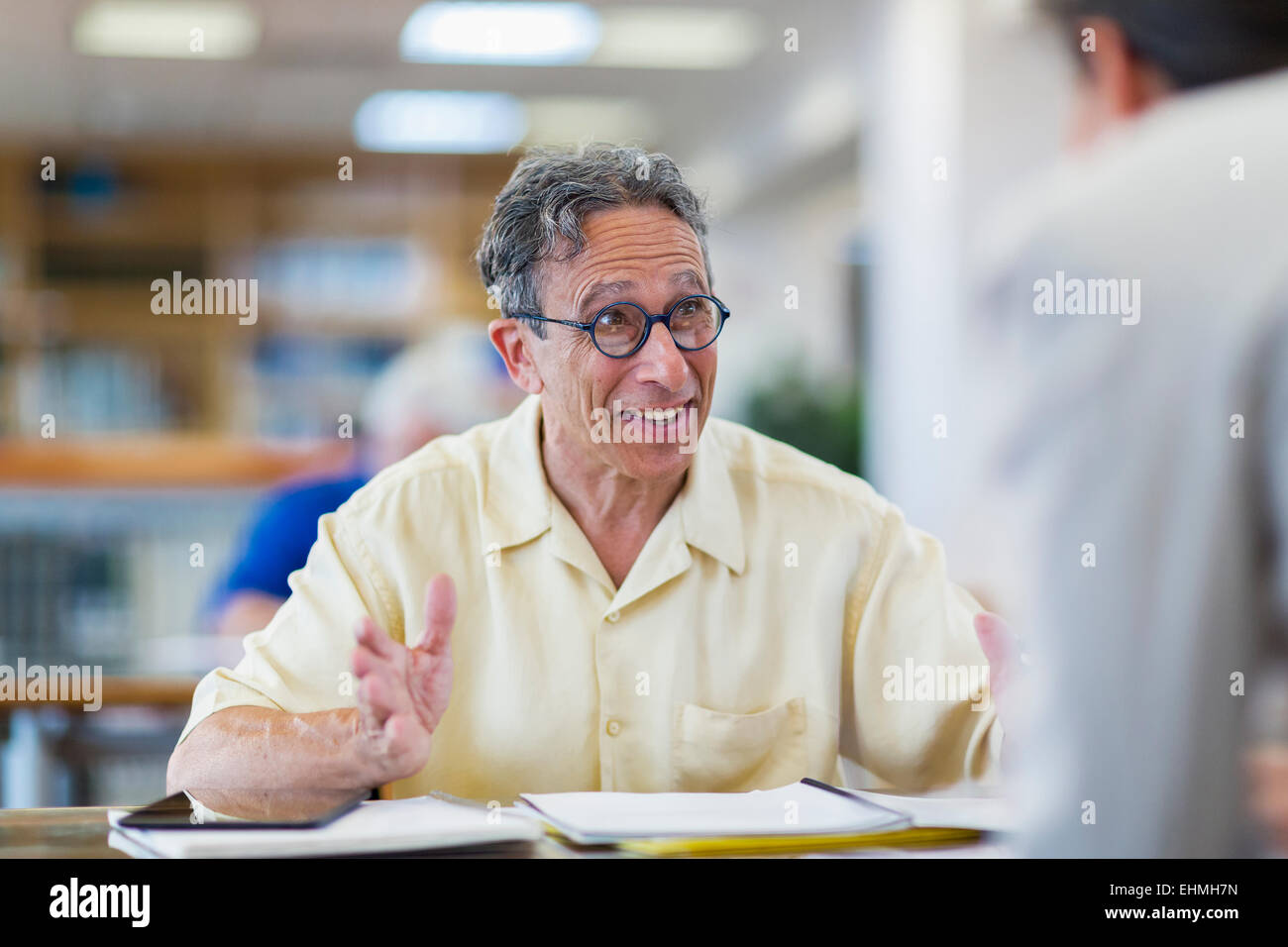 Docente aiutare lo studente adulto nella libreria Foto Stock