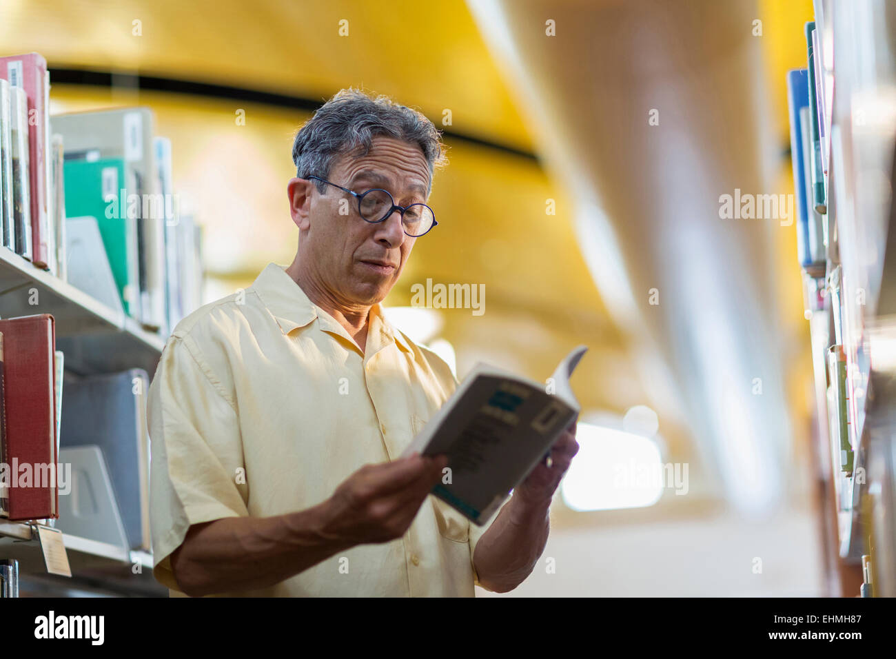 Vecchio uomo caucasico la lettura di libro in biblioteca Foto Stock