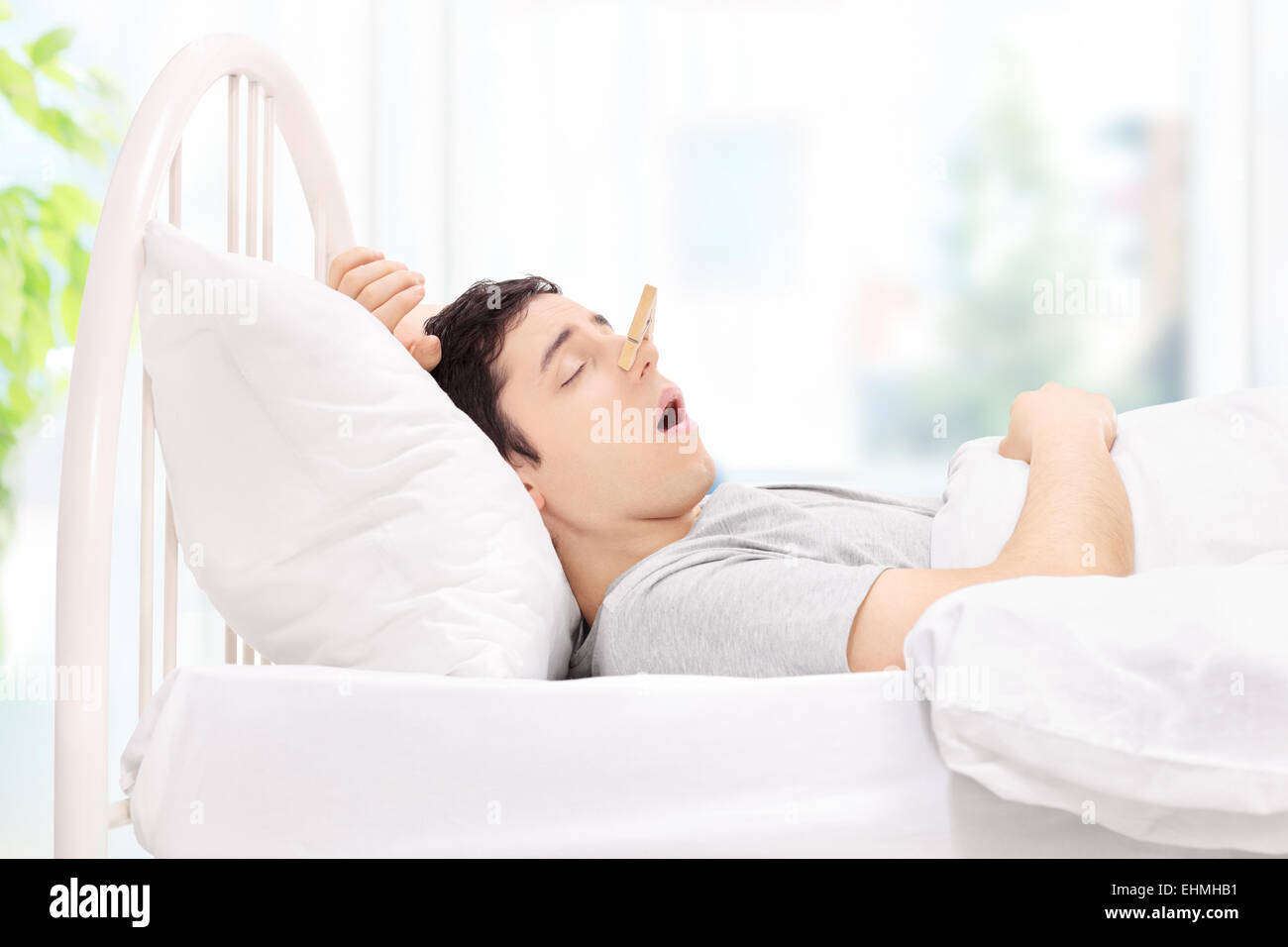 Uomo dorme con un clothespin sul suo naso a casa Foto Stock