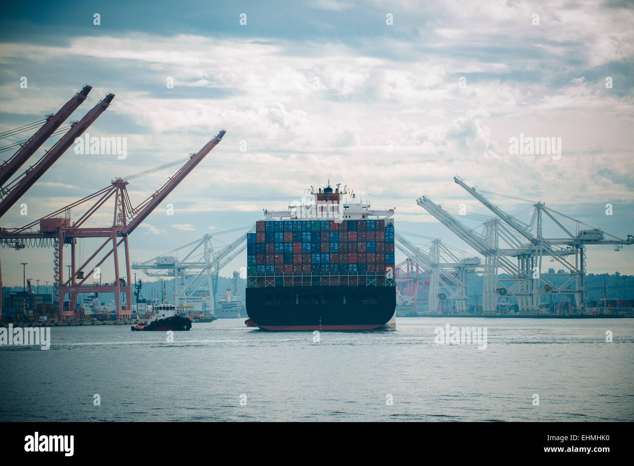 Rimorchiatore e nave portacontainer nel porto industriale Foto Stock