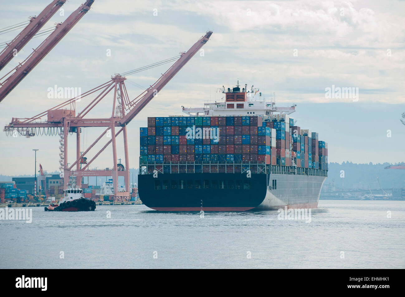Rimorchiatore e nave portacontainer nel porto industriale Foto Stock