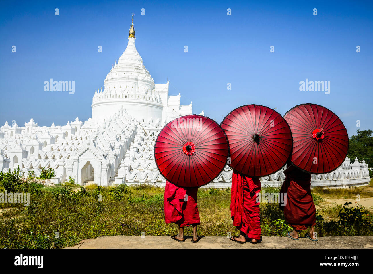 Monaci asiatici sotto gli ombrelloni visualizzazione storico tempio, Mingun, Mandala, Myanmar Foto Stock