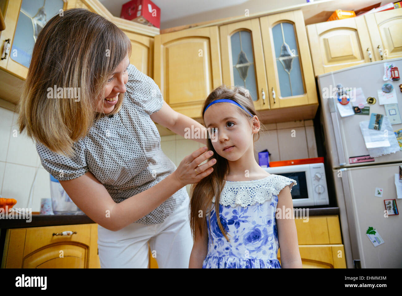 Mom rende la figlia acconciatura in cucina Foto Stock
