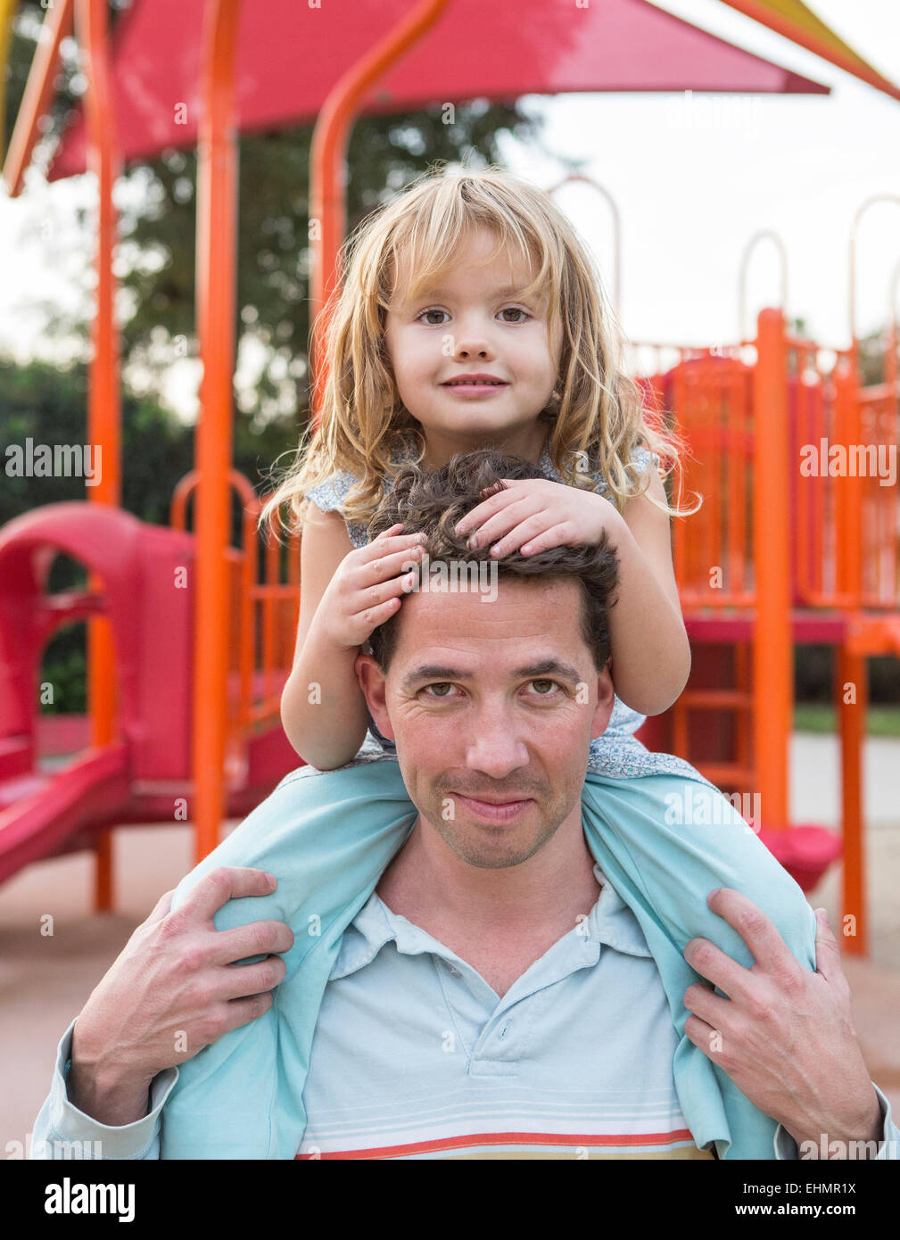 Padre caucasica holding figlia al parco giochi Foto Stock