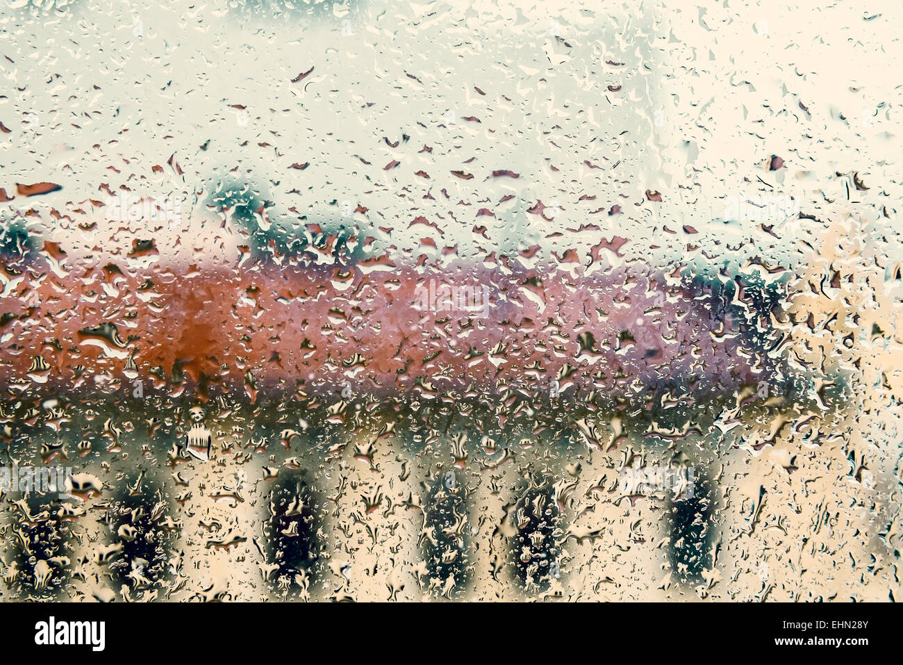 Sfondo di pioggia con un flusso verso il basso di gocce di acqua sul vetro del finestrino, vintage tonica foto con tonalità effetto filtro Foto Stock