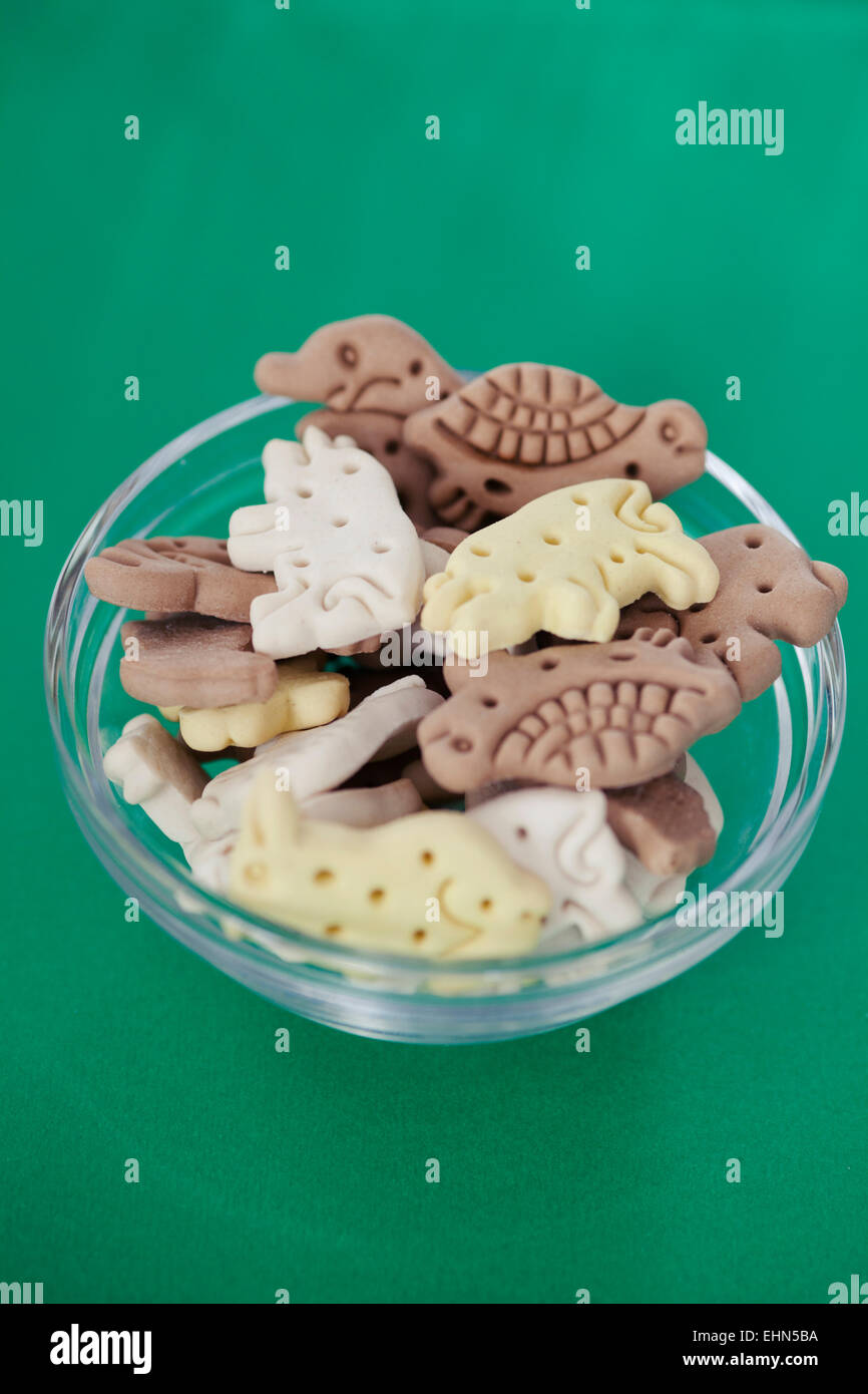 Cereali biscotti del cane in diversi colori su sfondo verde Foto Stock