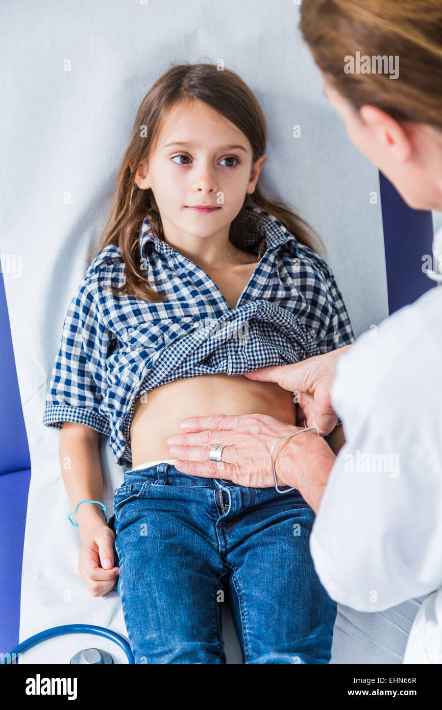 Medico di esaminare una giovane ragazza in addome. Foto Stock