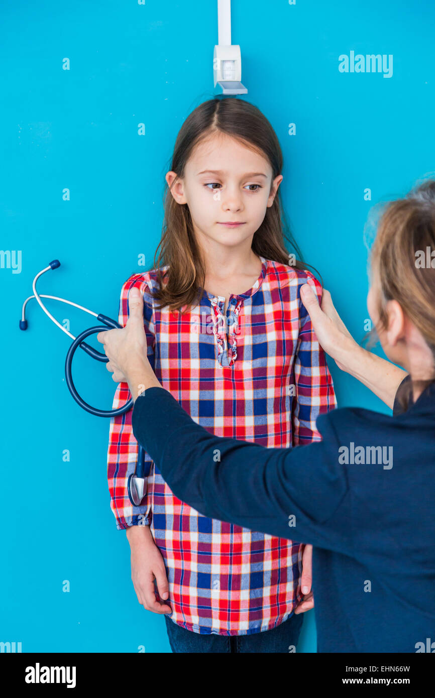 Medico la misurazione dell'altezza di una giovane ragazza durante un check-up. Foto Stock