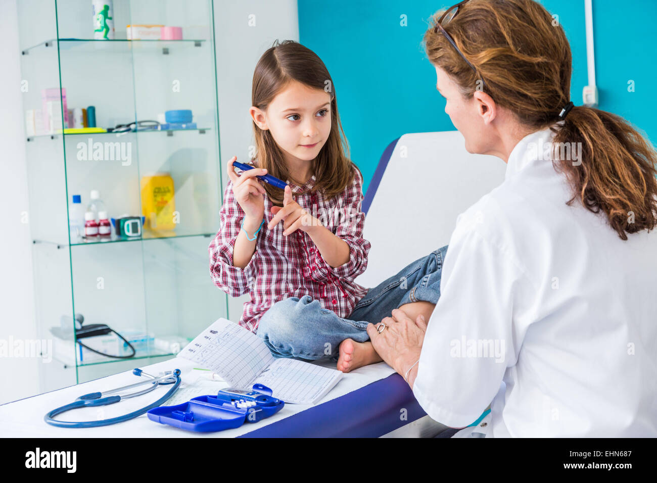 Pazienti diabetici di 7 anno- vecchia ragazza ascoltando il suo medico spiegare come utilizzare un tipo di siringa da insulina. Foto Stock