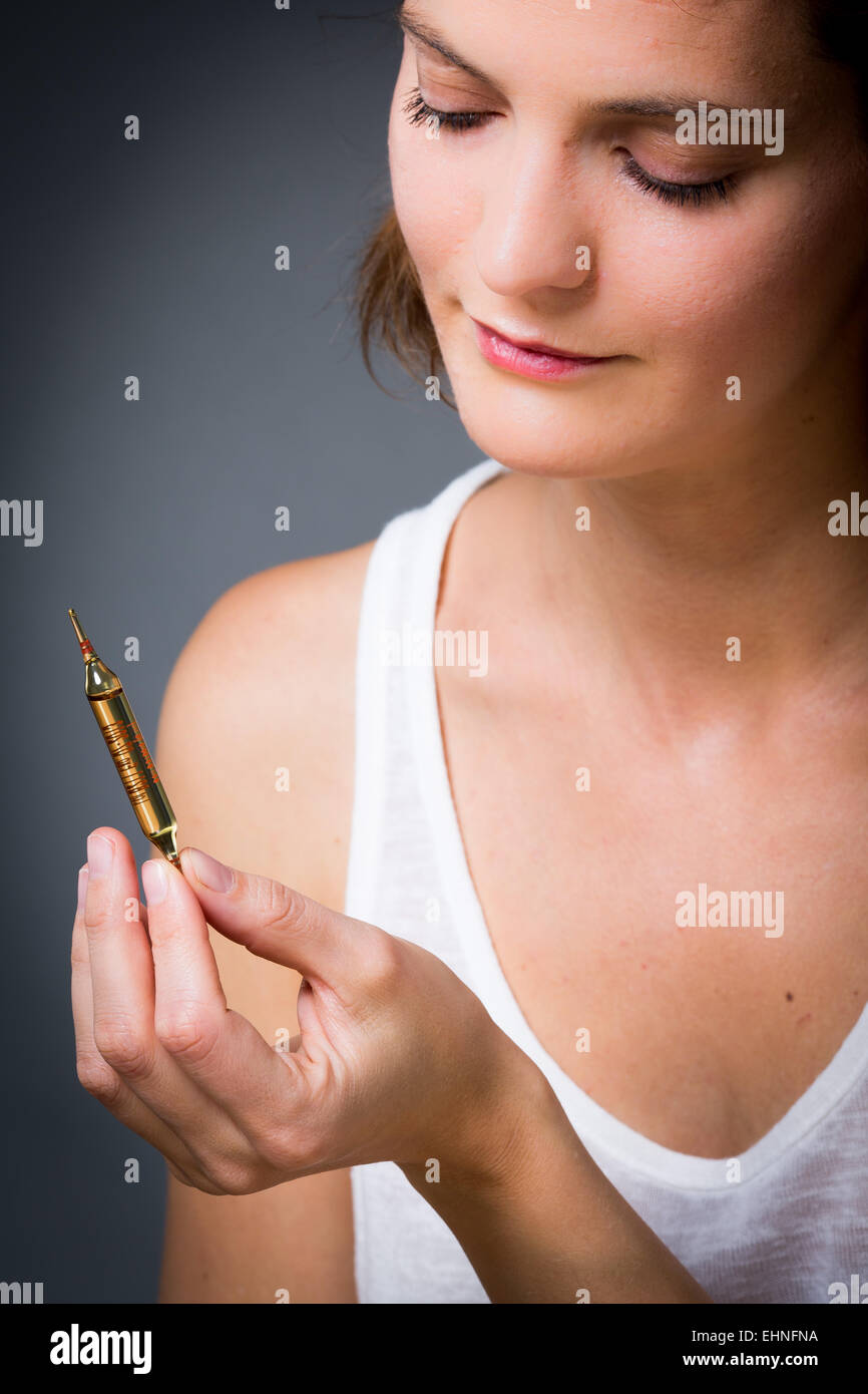 Donna che mantiene la fiala di vetro di vitamina D. Foto Stock