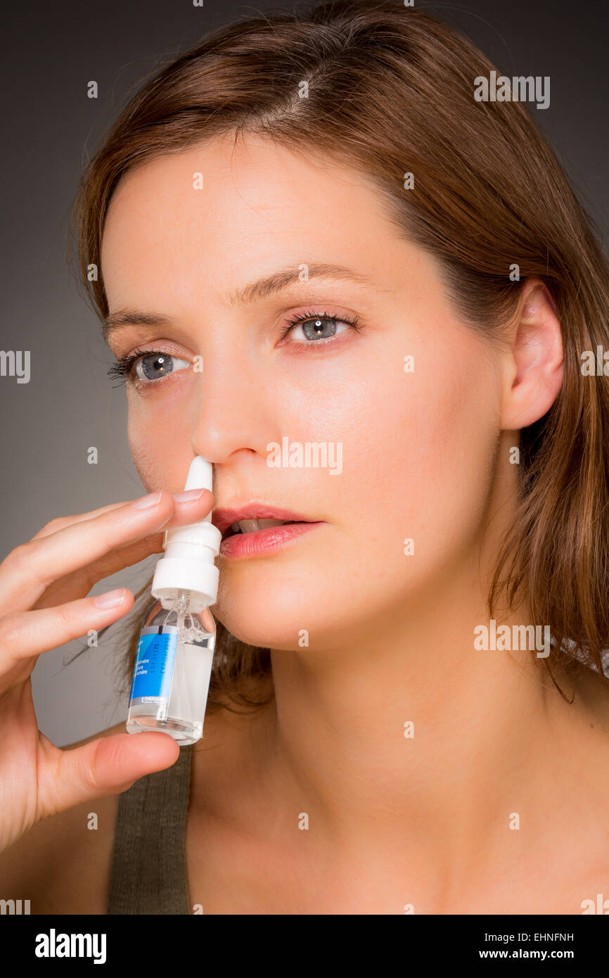 Donna che utilizza uno spray nasale per controllare la rinite. Foto Stock