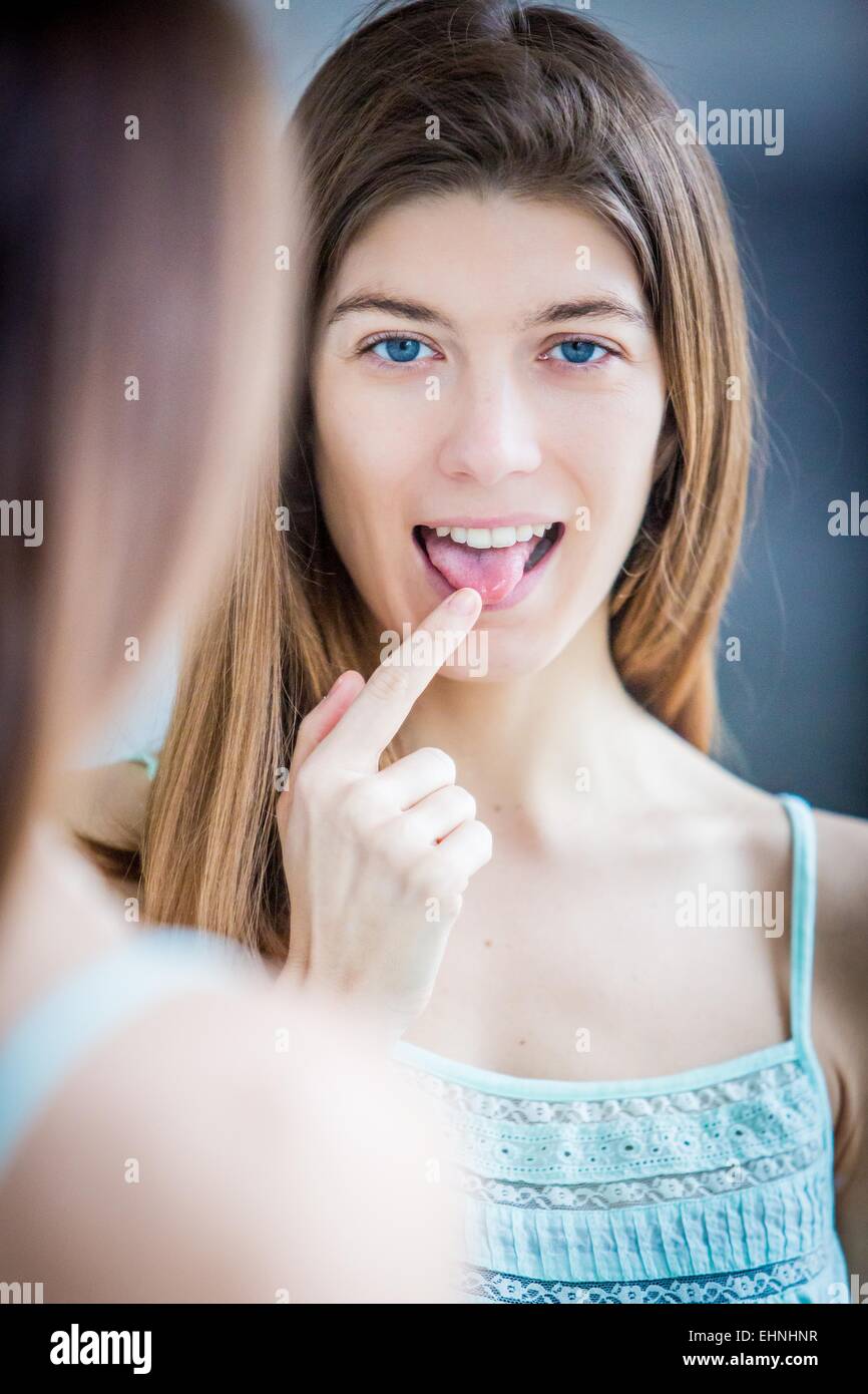 Donna esaminando la sua lingua in uno specchio. Foto Stock