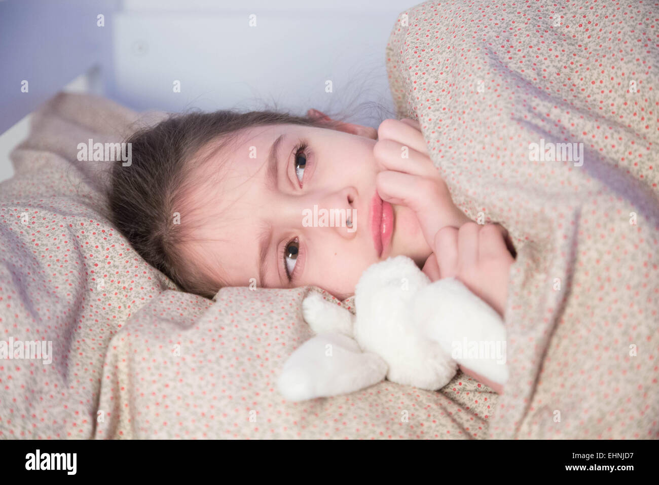 7 anno-vecchia ragazza sdraiato sul letto. Foto Stock