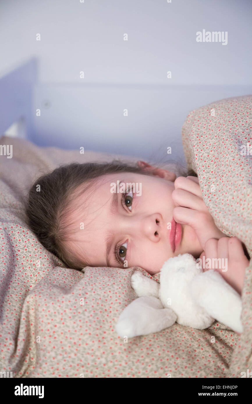 7 anno-vecchia ragazza sdraiato sul letto. Foto Stock