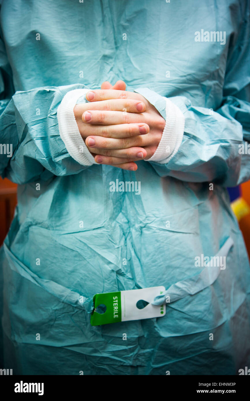 L'infermiera che indossa una sterile camici chirurgici. Foto Stock