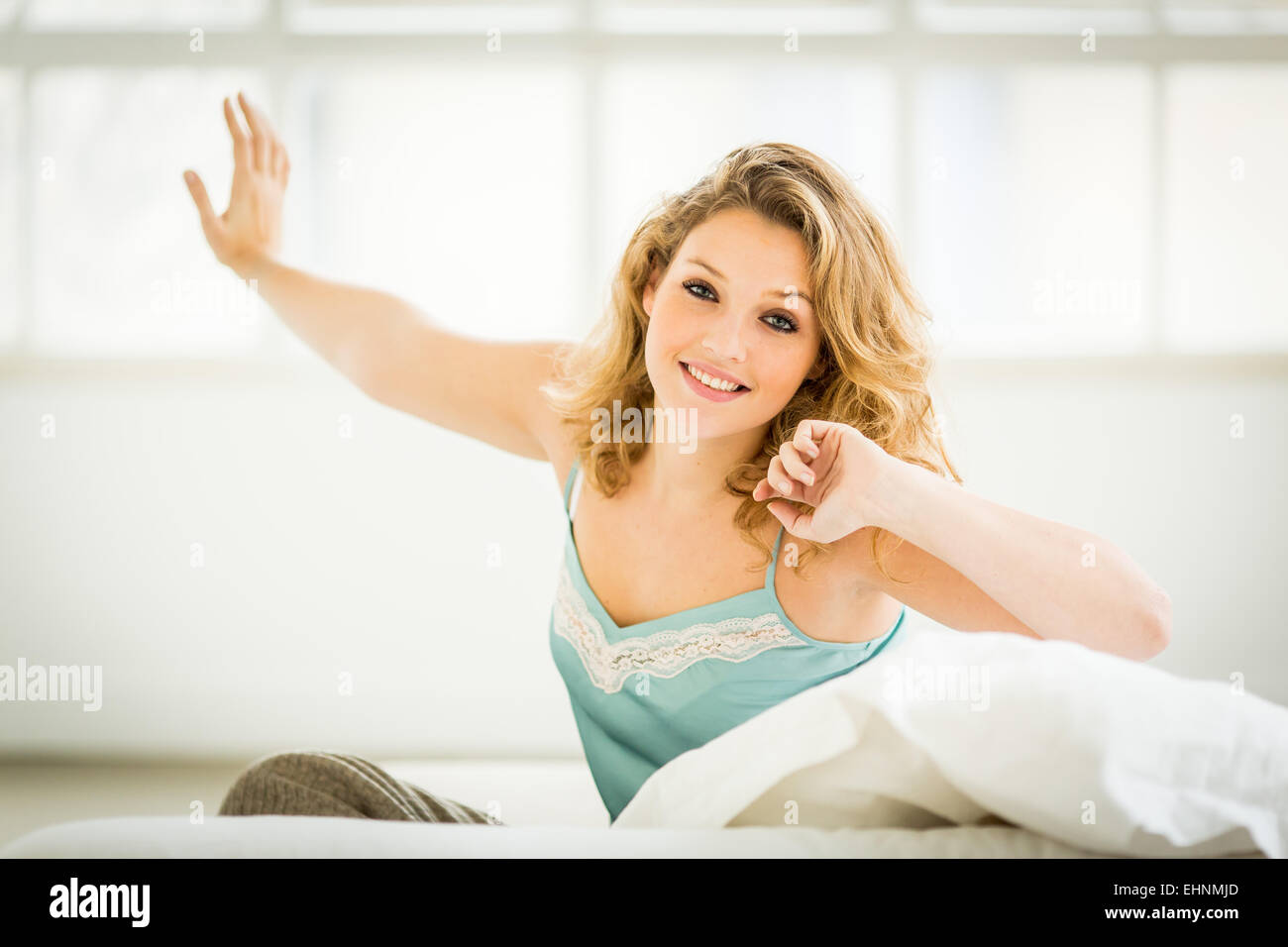 Donna di svegliarvi e stretching nel letto. Foto Stock