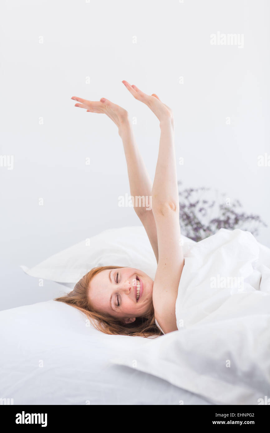 Donna di svegliarvi e stretching nel letto. Foto Stock