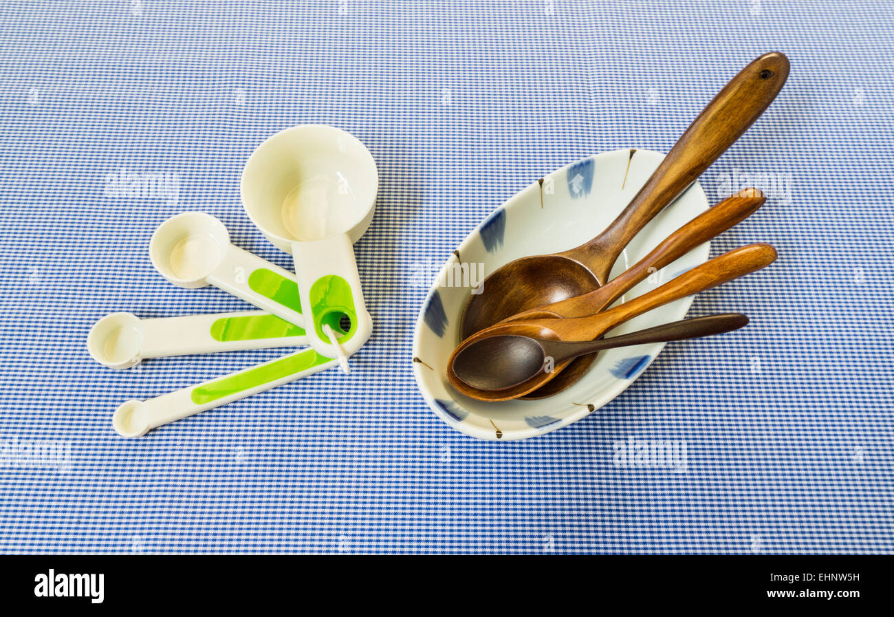 Misurare cucchiaio insieme con 4 cucchiaio di legno sulla ciotola bianco posto su sfondo quadrato Foto Stock