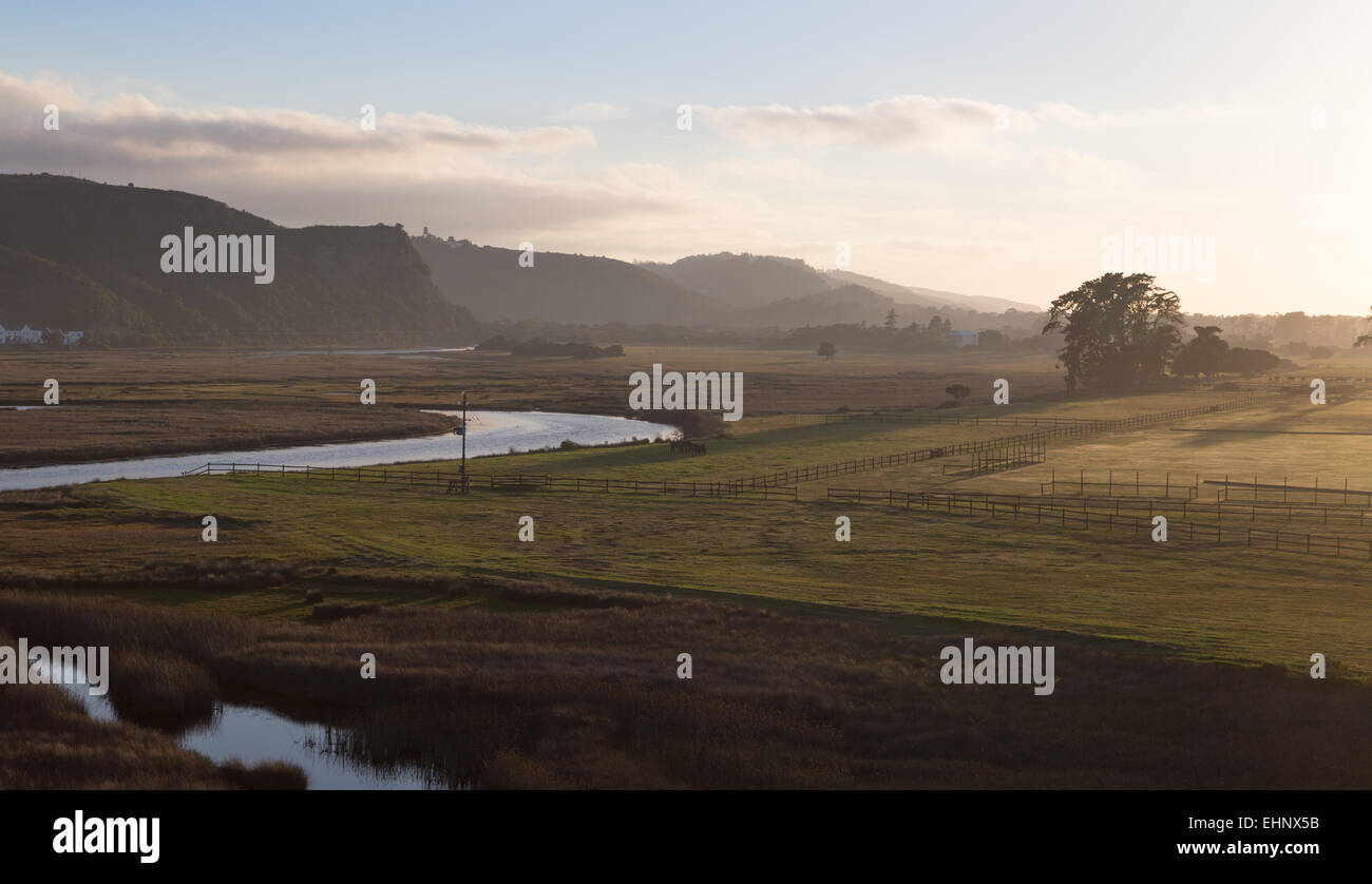 Bella vista la mattina il più assonnato i campi e il fiume di un cavallo stabile e le montagne a Plettenburg Bay, Sud Africa Foto Stock