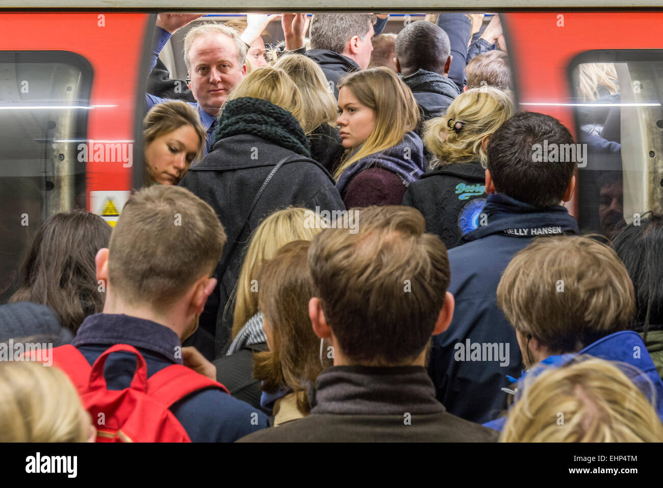 Londra, Regno Unito. 16 marzo, 2015. I passeggeri attendono pranzo Northern Line treni a Stockwell station. Essi sono bombardati da annunci che tutte le linee che hanno un buon servizio e si trovano di fronte ad un utile segno, condizionati da TFL, dicendo loro di non si affollano attorno a una porta. Purtroppo sono costretto dal peso di numeri per stand pericolosamente vicino al bordo della piattaforma. Stockwell Station sulla linea del Nord, Londra Unerground, 16 Mar 2015. Credito: Guy Bell/Alamy Live News Foto Stock