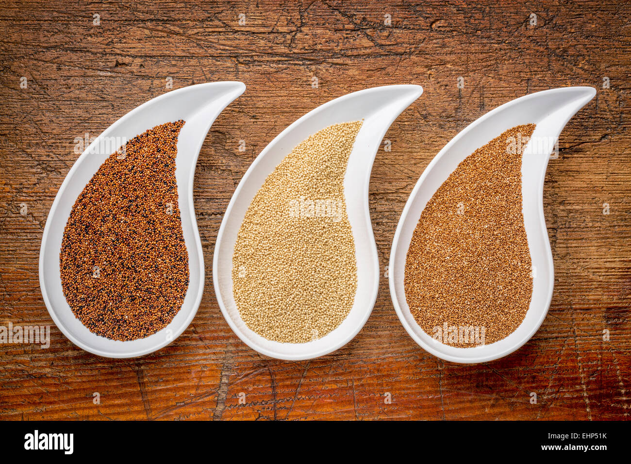 I tre piccoli senza glutine cereali - kaniwa, amaranto e teff a forma di lacrima bocce contro legno rustico Foto Stock