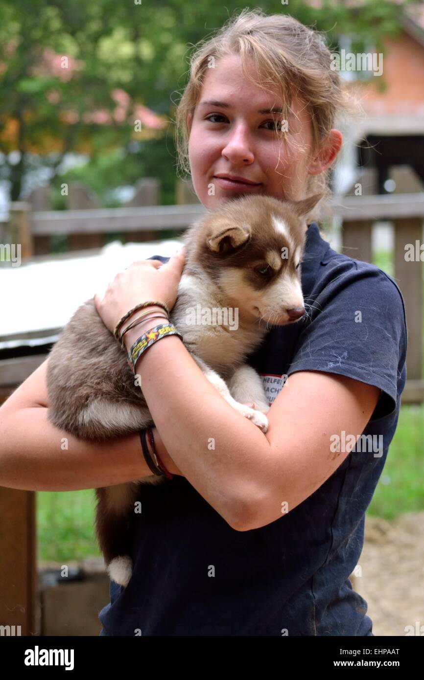 Adolescente detiene husky cucciolo nelle sue braccia Foto Stock