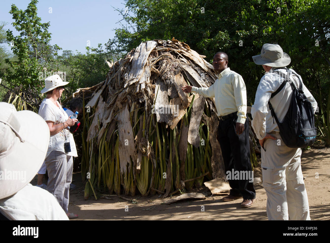 La guida spiega alcuni turisti sui popoli Hadzabe case. Foto Stock