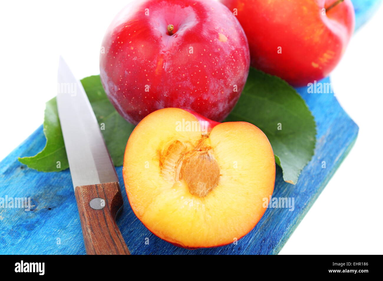 Intero e metà di prugna sulla scheda blu. Foto Stock