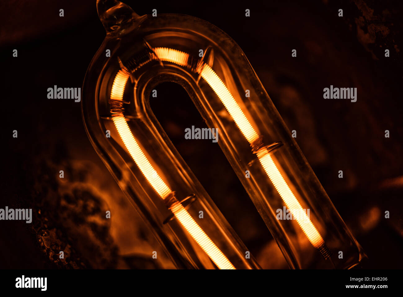 Il filamento incandescente di una 1000 lampada alogena al quarzo con scaglie di metallo e danni termici al riflettore e di erogatore di calore Foto Stock