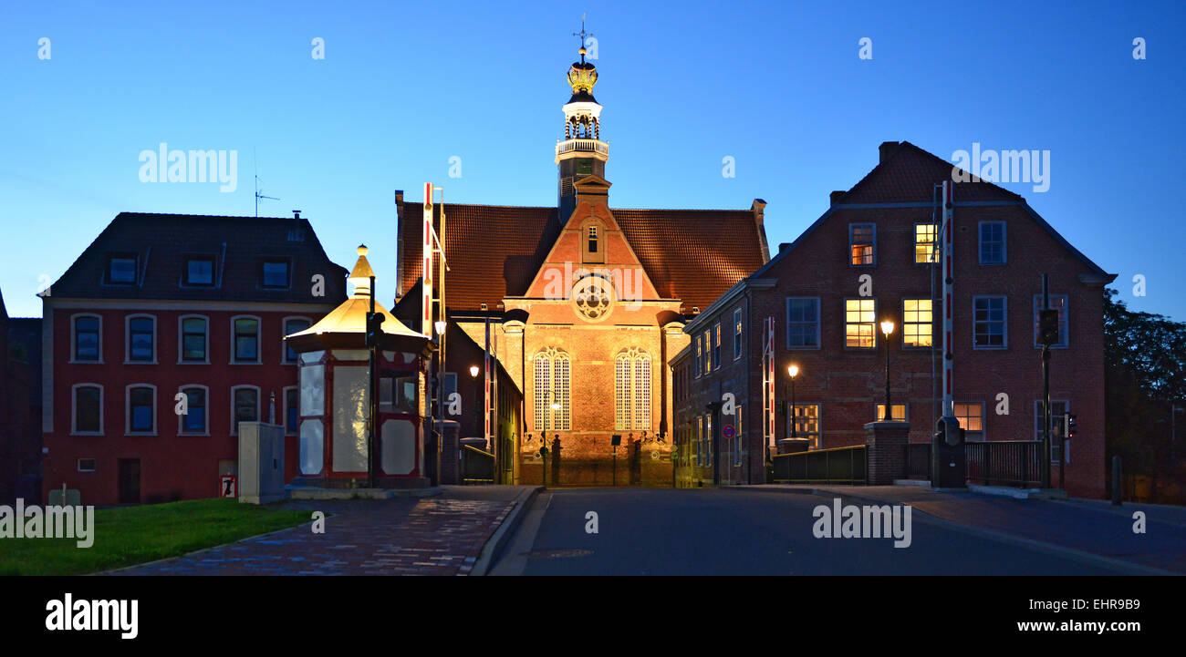 Nuova chiesa illuminata dietro il nuovo ponte a bilico sul rosso siel, Emden, Frisia orientale, Bassa Sassonia, Germania Foto Stock