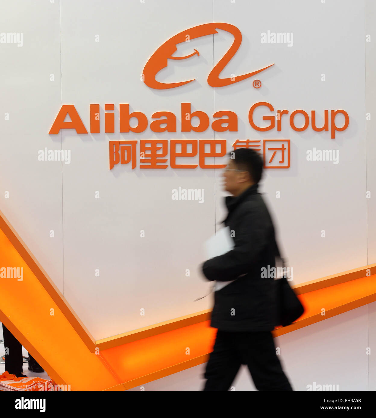Passeggiate a piedi oltre il logo Alibaba che viene visualizzato sulla parete del Alibaba Group Holding Ltd mostra al CeBit tech show di Hannover, Germania, lunedì, 16 marzo 2015 Foto Stock