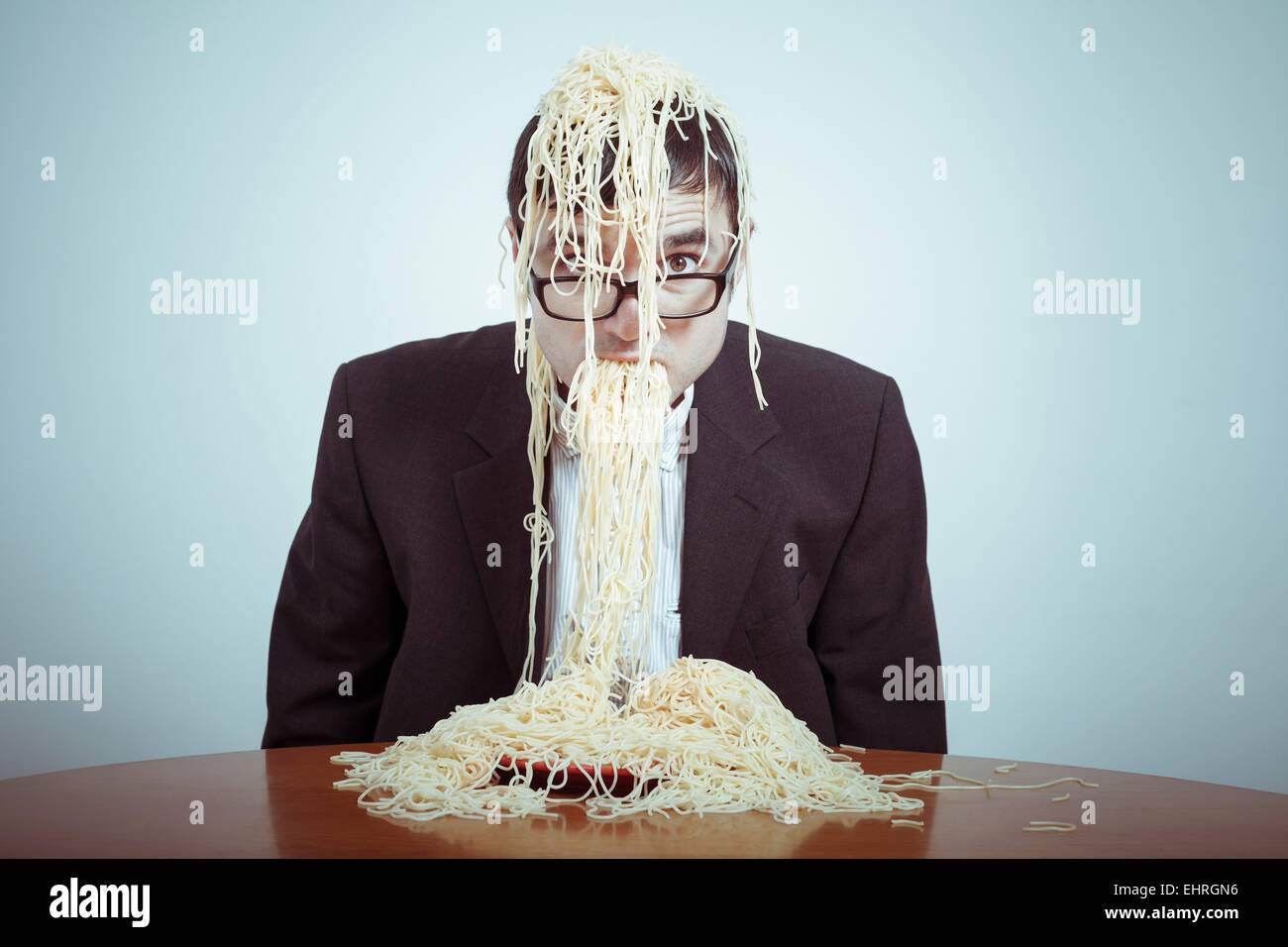 Surriscaldamenti e il consumismo concetto. Nasty imprenditore mangiare pasta. Foto Stock