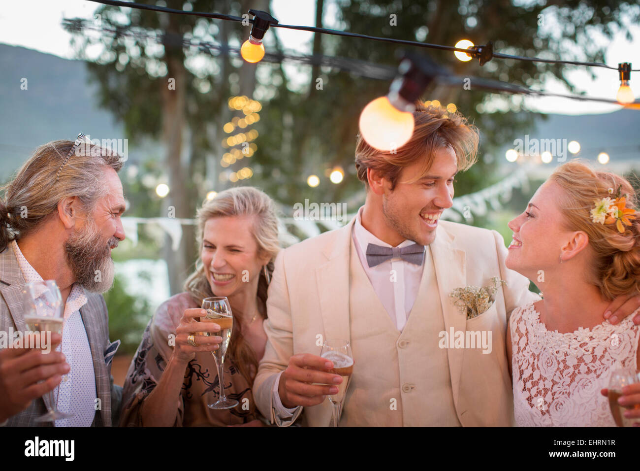 Coppia giovane e i loro ospiti con champagne flauti durante il ricevimento di nozze in giardino Foto Stock
