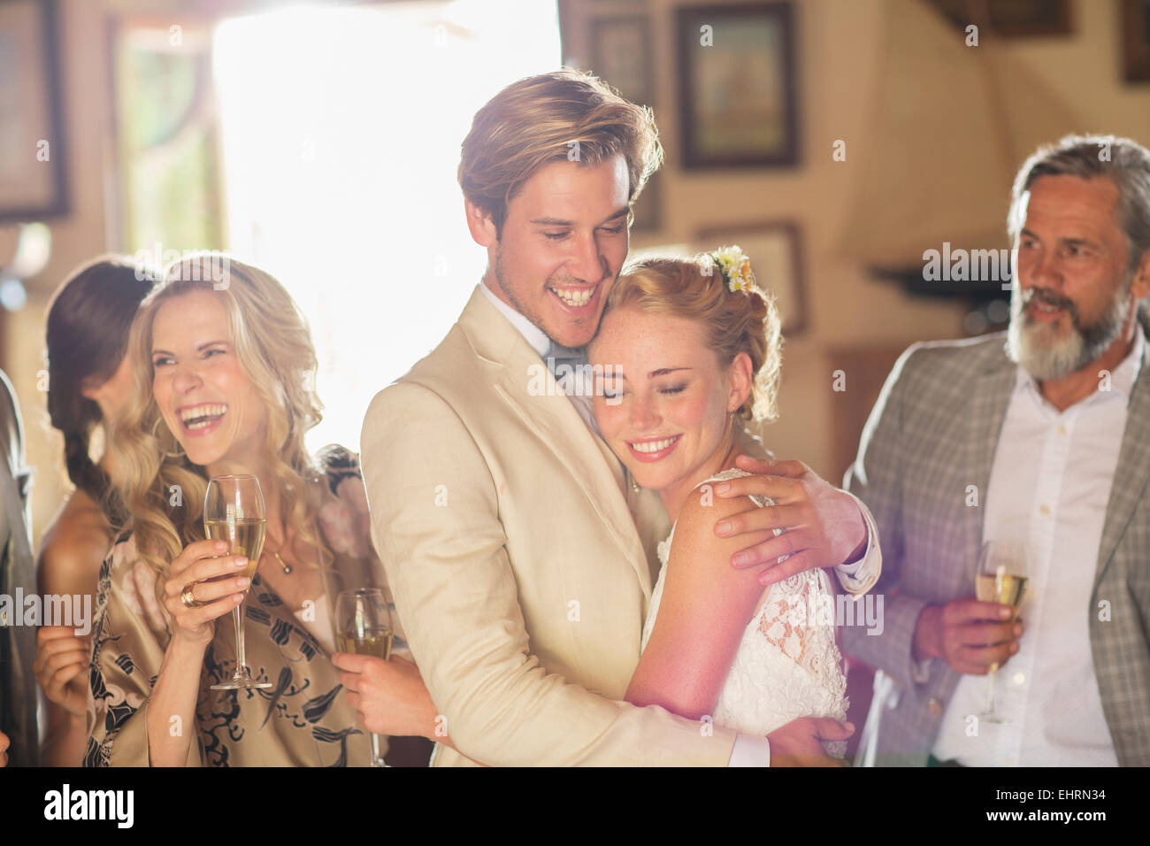Coppia giovane e gli ospiti al ricevimento di nozze nella camera interna Foto Stock